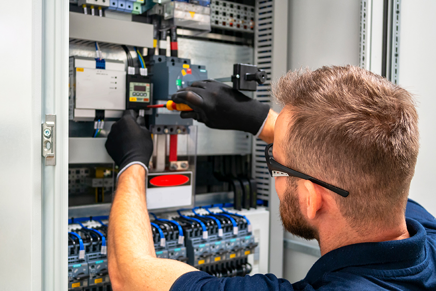 A contractor working in an electrical fuse box, illustrating how KWB works with local and national contractor businesses to provide a responsive block management service
